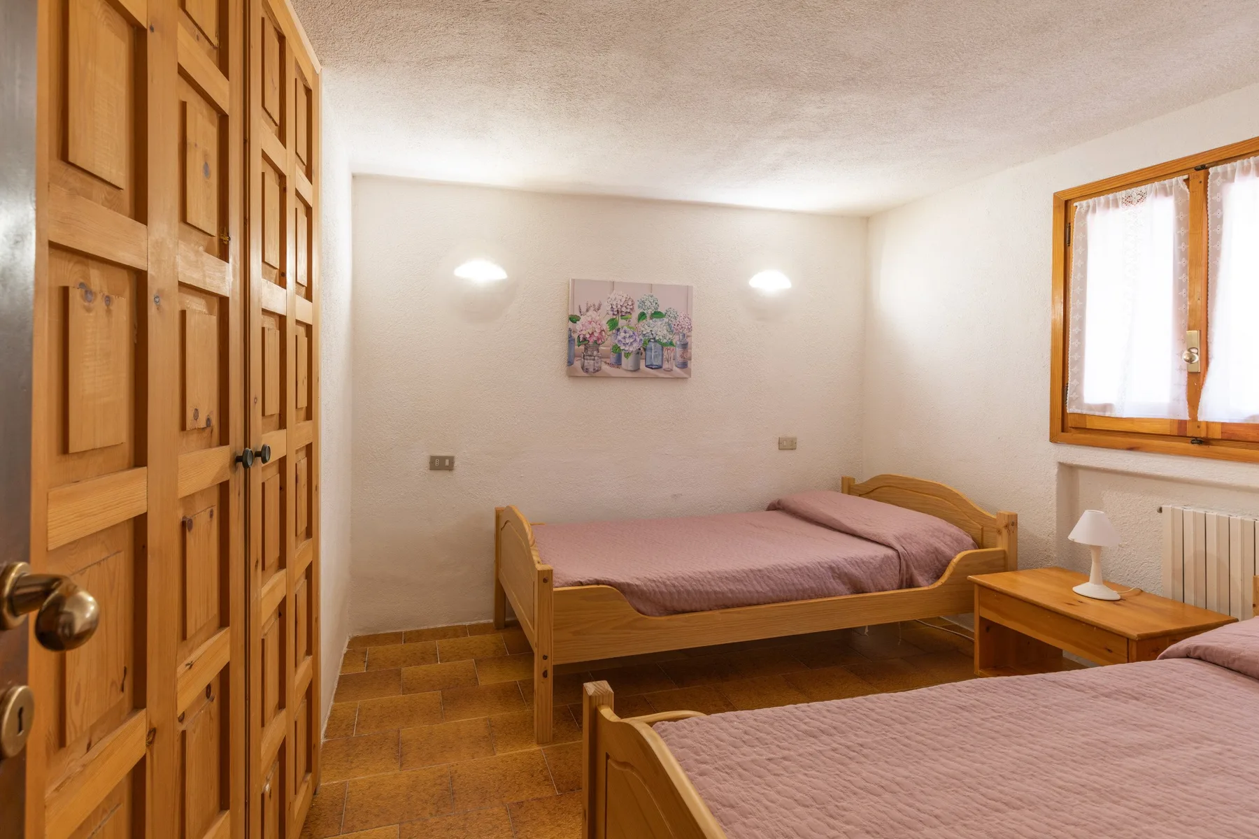 A bedroom with wooden beds, a wardrobe, and a window.