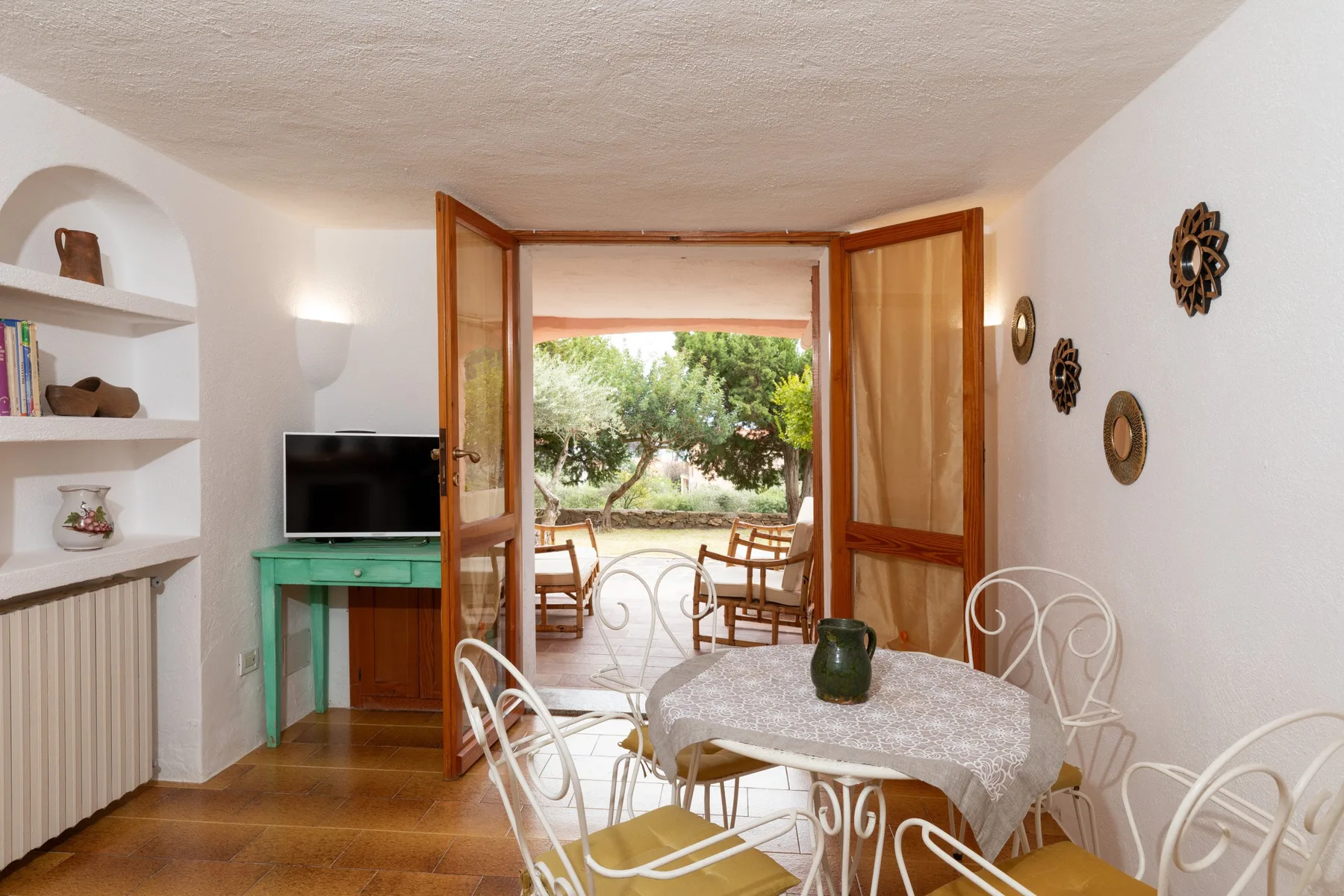 A dining area opens onto a patio with outdoor seating and greenery.