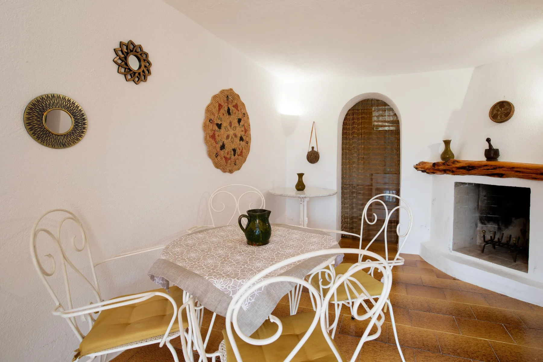 A dining area with a table and white metal seating beside a fireplace.