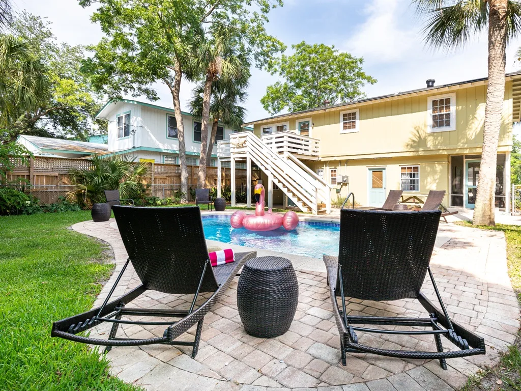 A backyard pool area with lounge seating and a two-story building.