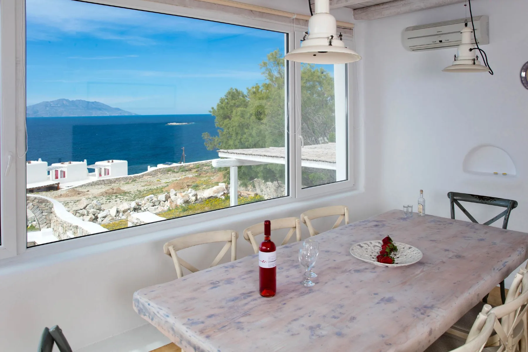 A dining area with a table beside a large window overlooking the sea.
