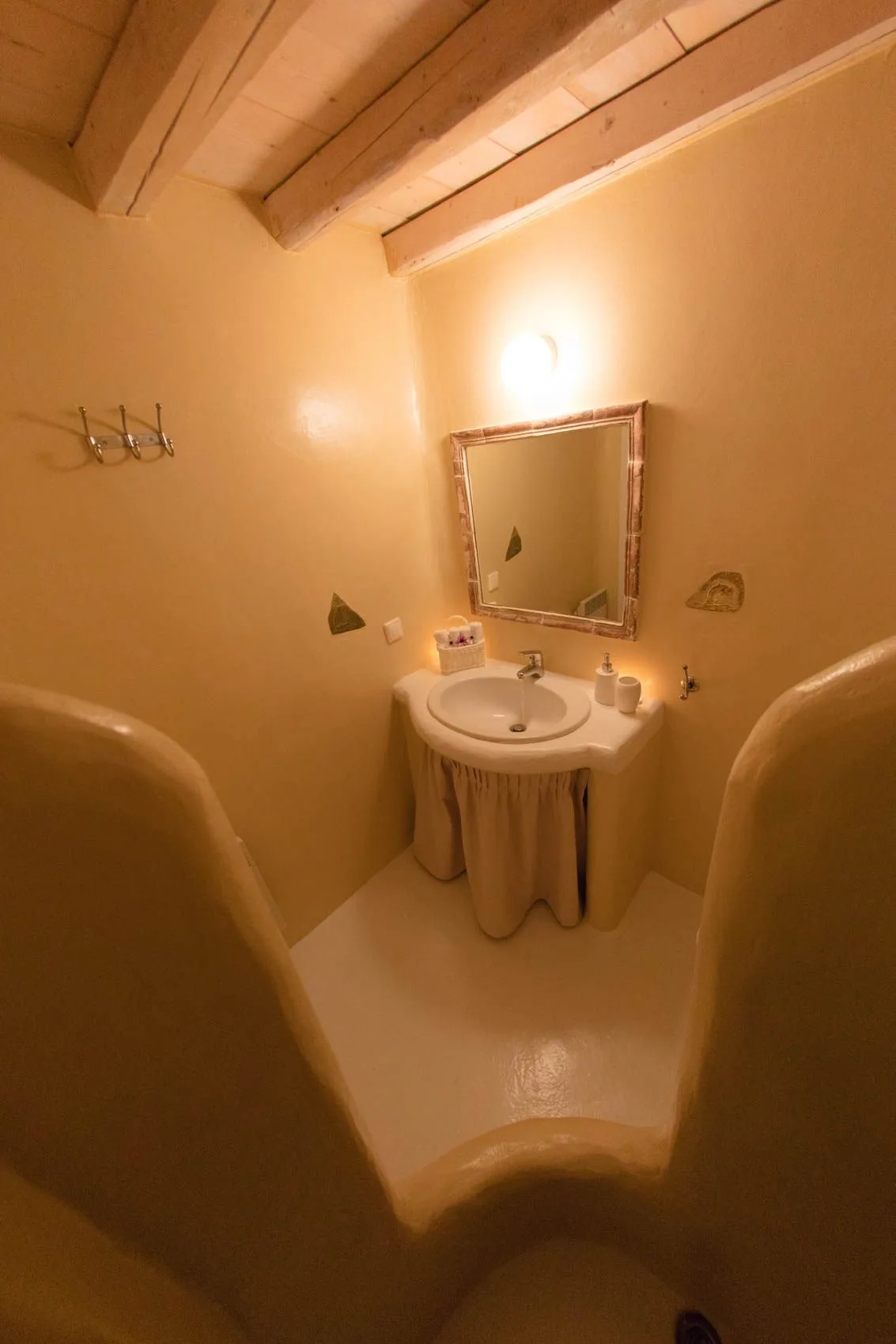 A warm-toned bathroom with a sink, mirror, and wall light.