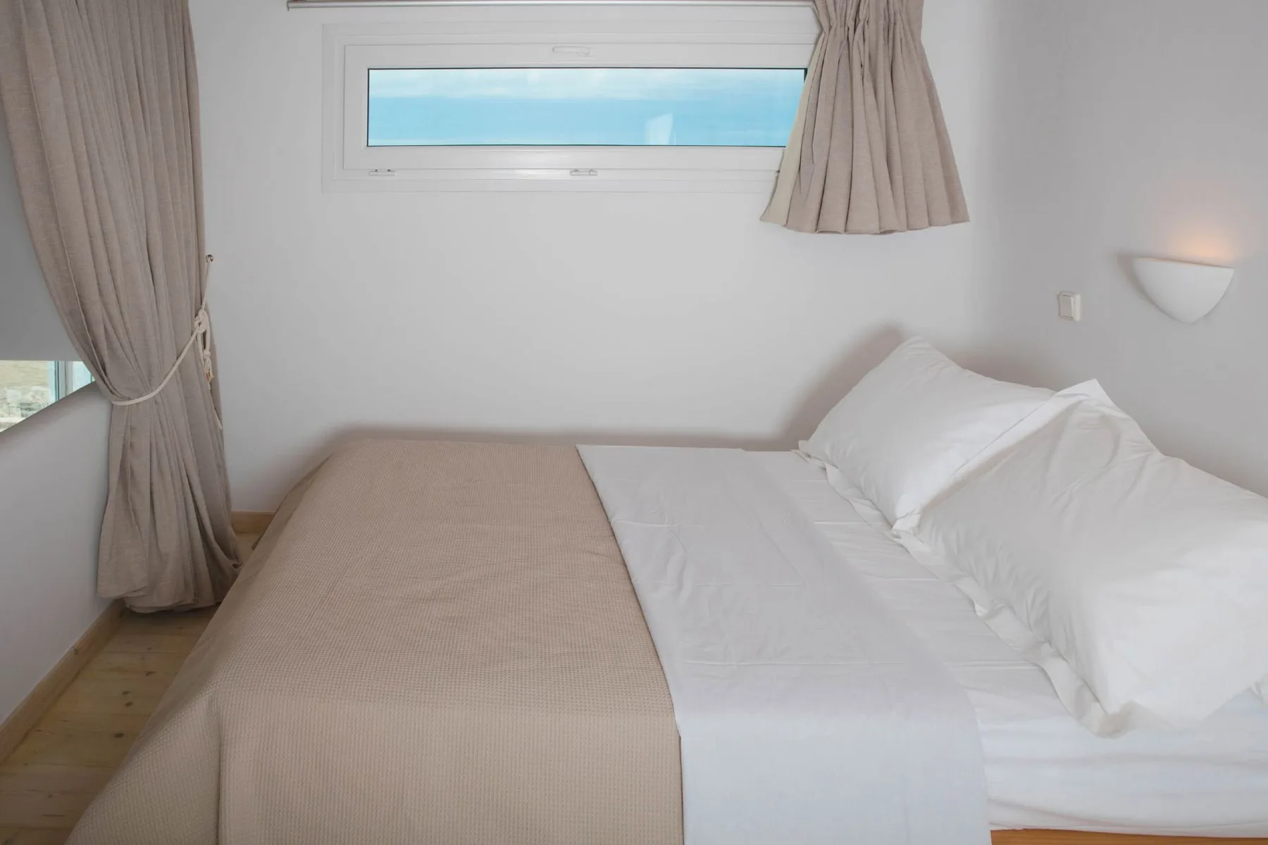 A bedroom with a neatly made bed and a window above it.