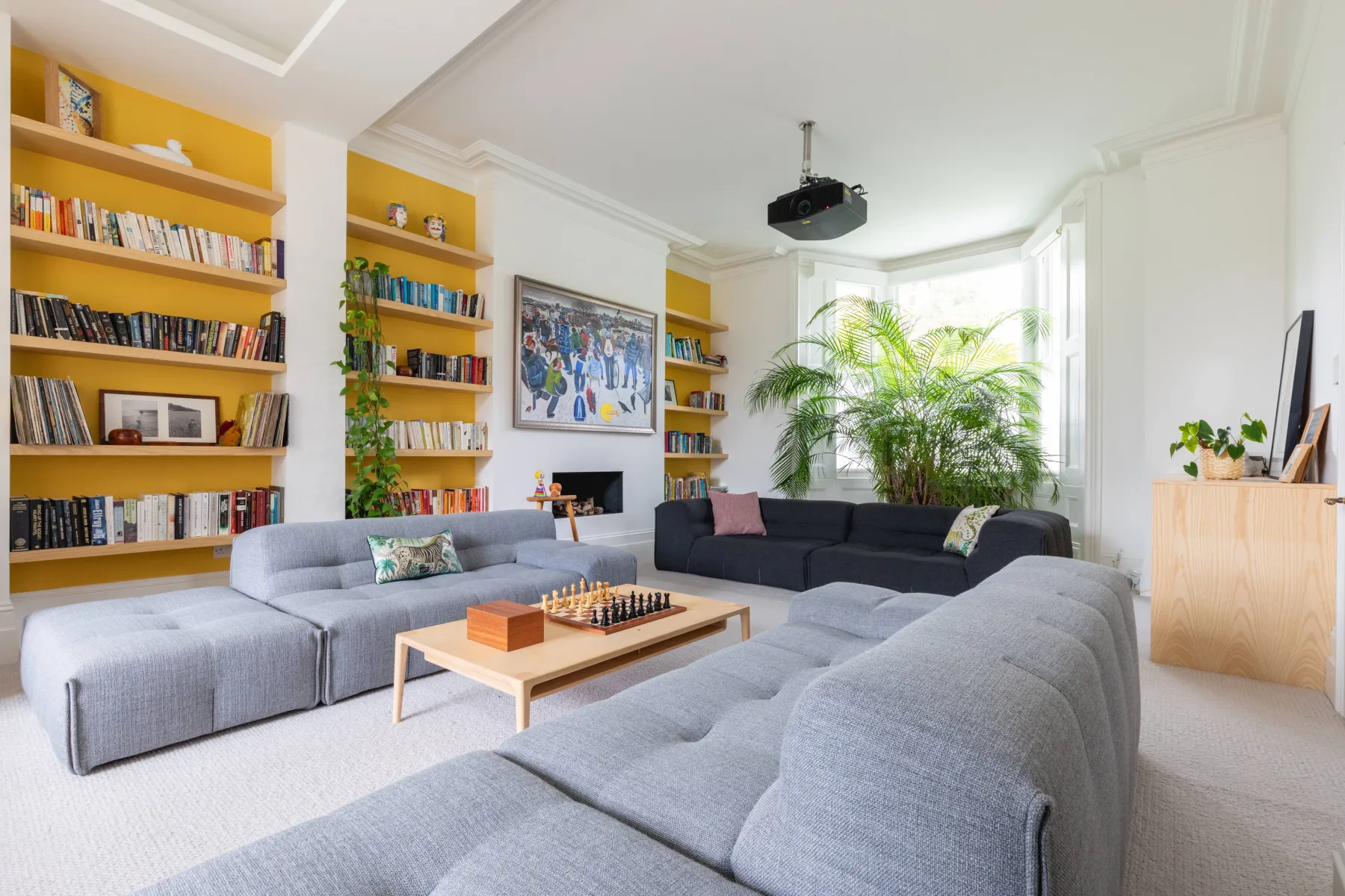 A bright living room with seating, bookshelves, and a coffee table.