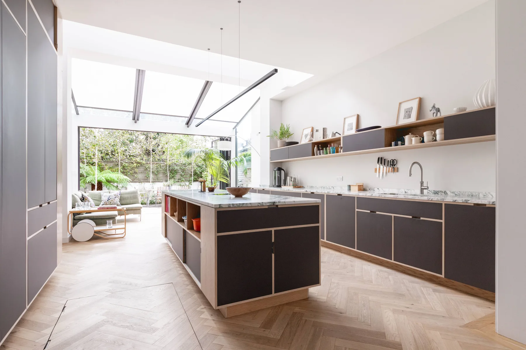 A bright modern kitchen with a central island and an adjoining lounge area.