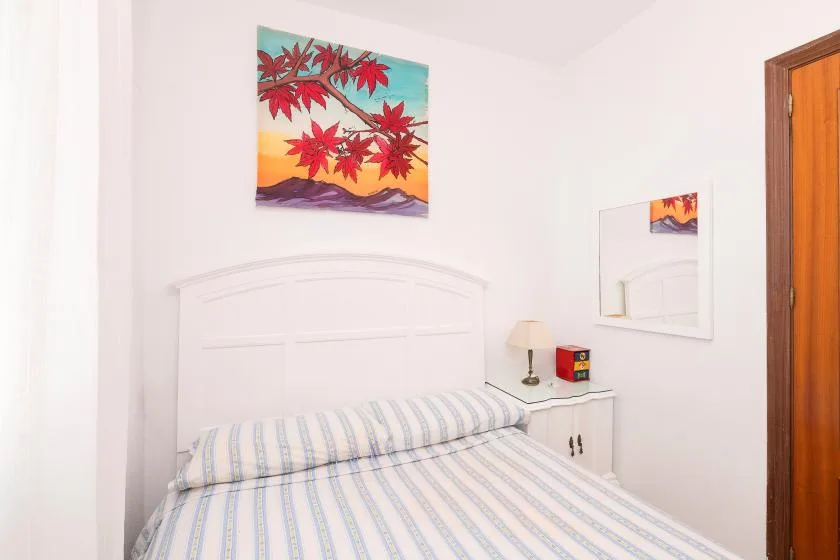 A bedroom with a striped bedspread and colorful wall art.