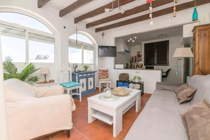 A living room with seating around a white coffee table and arched windows.