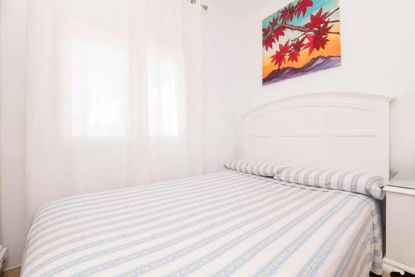 A bedroom with a bed beneath colorful floral wall art.