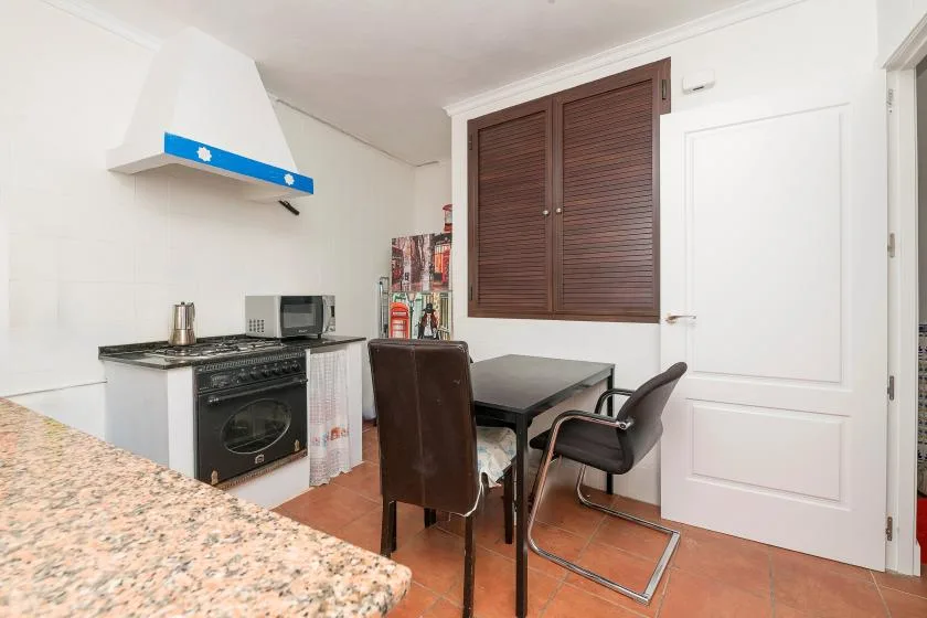 A kitchen and dining area with a table, seating, and cooking appliances.