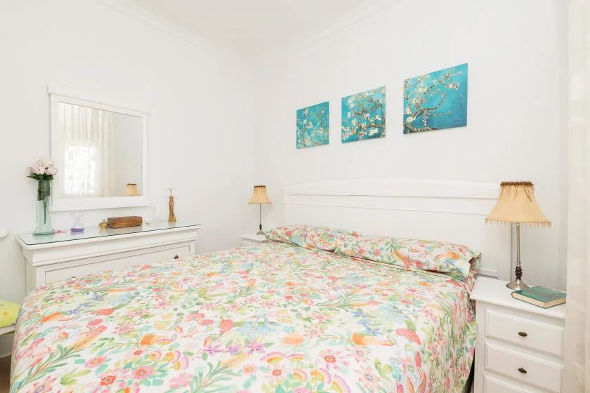A bedroom with a bed covered in colorful floral bedding and matching bedside tables.