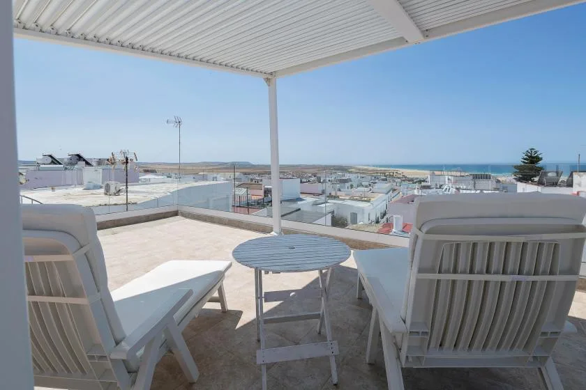 A covered rooftop terrace with outdoor seating and views of the sea.