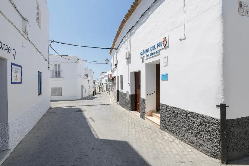 A narrow paved street runs between white buildings in a sunny village.