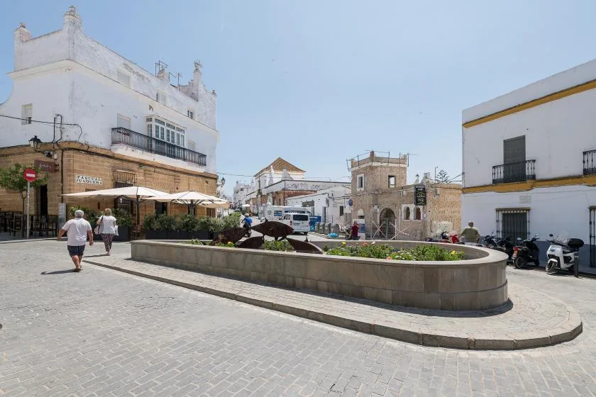 A paved town square with a long raised planter and surrounding buildings.