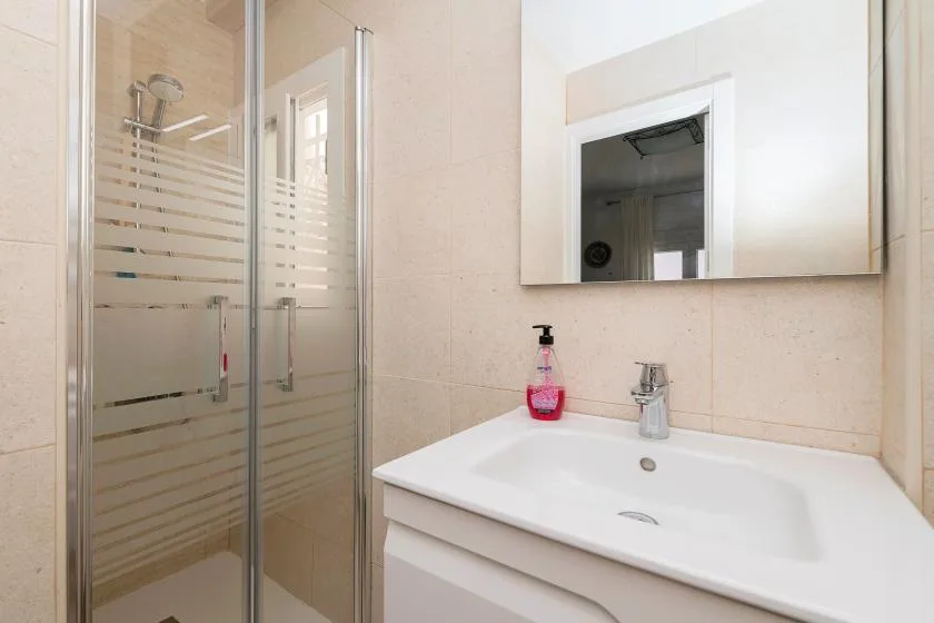 A bathroom vanity with a sink sits beside a glass shower.