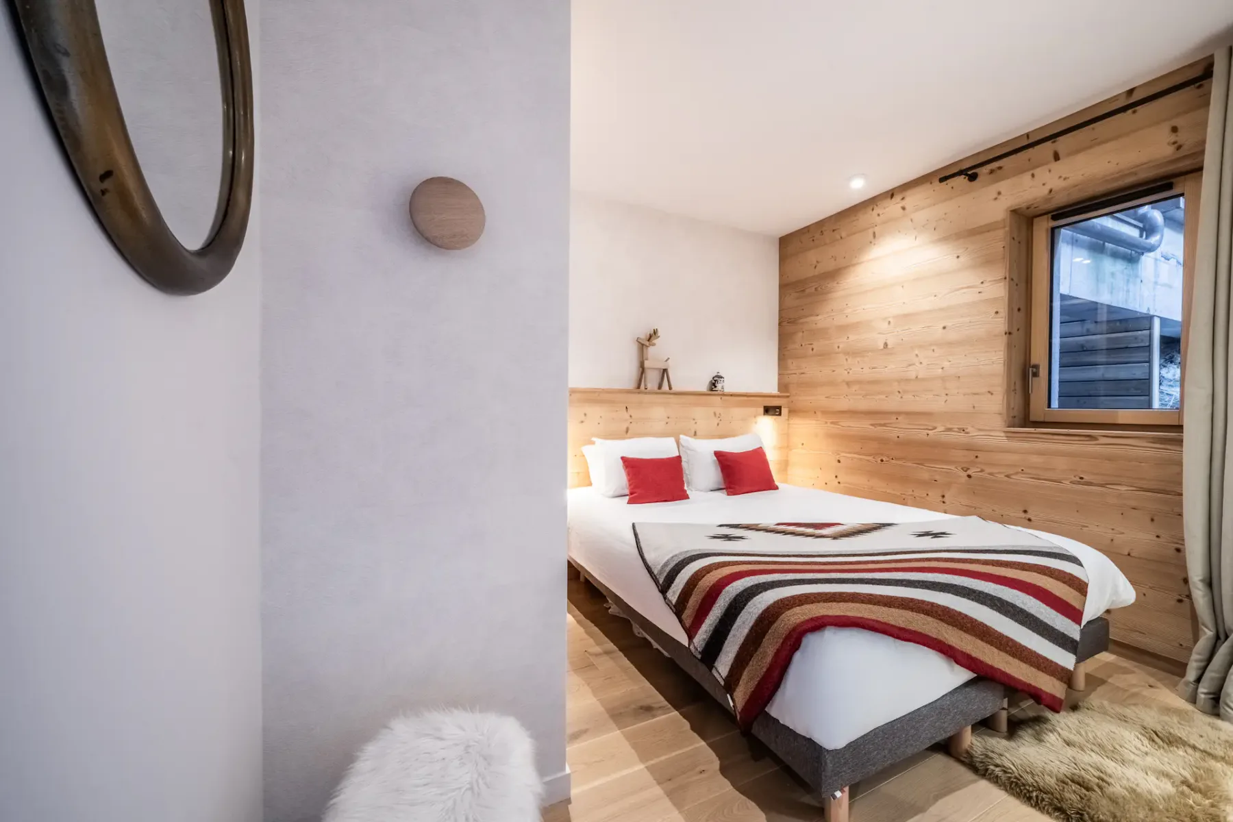 A bedroom with a bed, striped blanket, and wood-paneled wall.