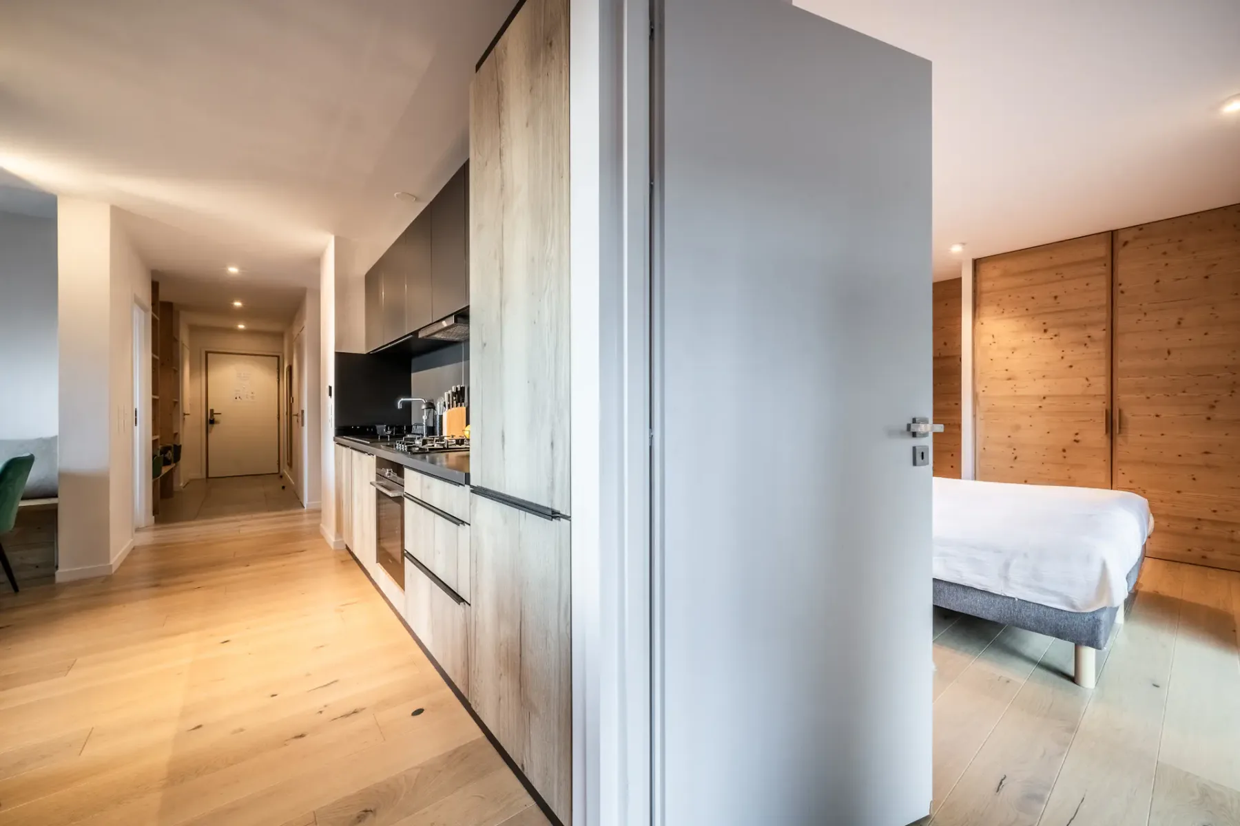 A hallway opens beside a compact kitchen, with a bedroom visible through the doorway.