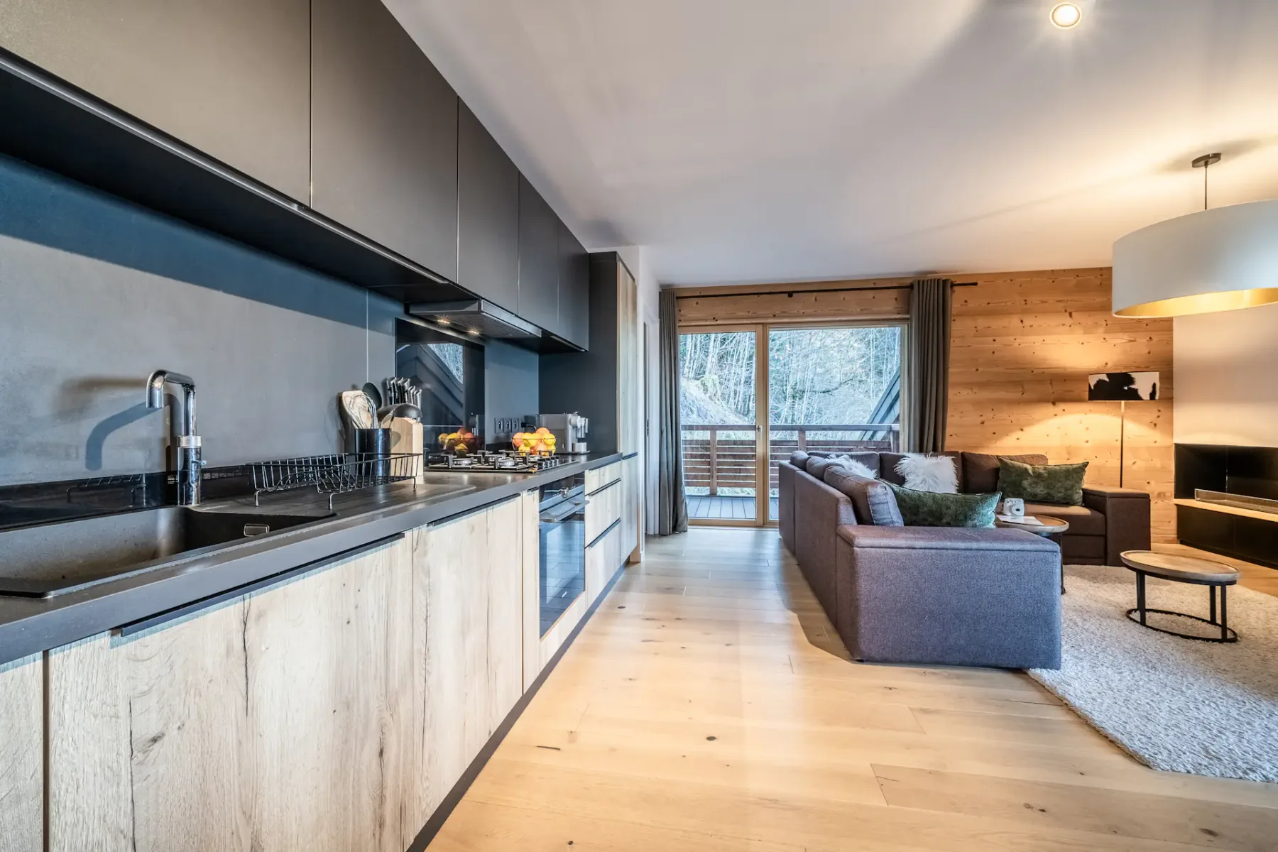 An open-plan kitchen and living area with a counter and seating by the window.