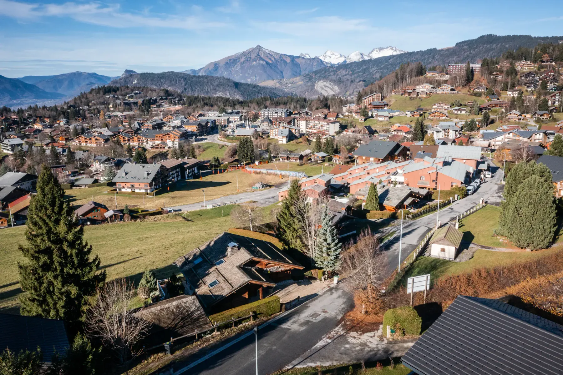 Aerial view of a mountain town with clustered buildings and snow-capped peaks in the distance.