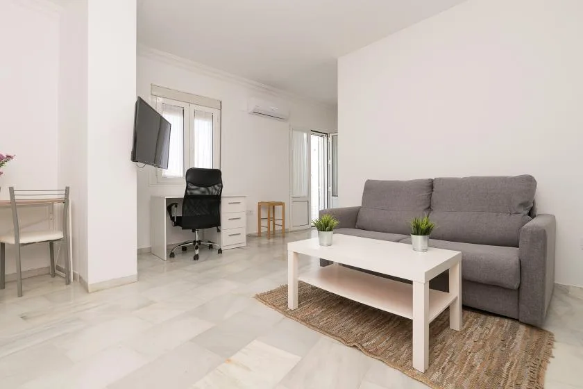 A living room with gray seating, a white coffee table, and a television.