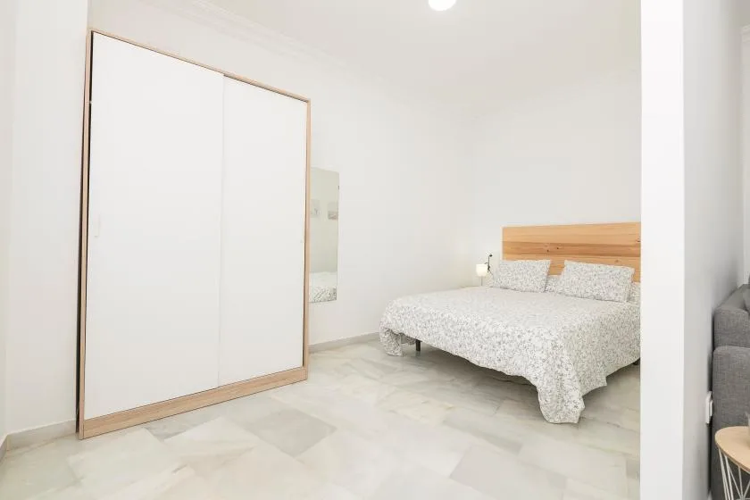 A bright bedroom with a bed and a large sliding wardrobe.
