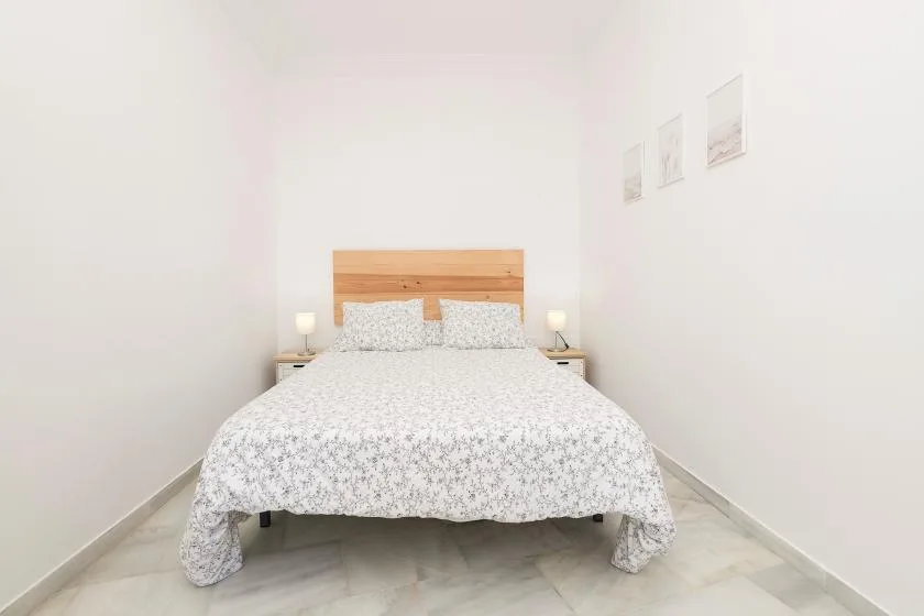 A bright bedroom with a double bed and a wooden headboard.