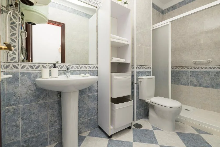 A tiled bathroom with a pedestal sink, toilet, and bathtub.