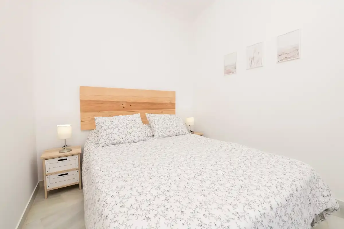 A bedroom with a bed covered in a light patterned bedspread.