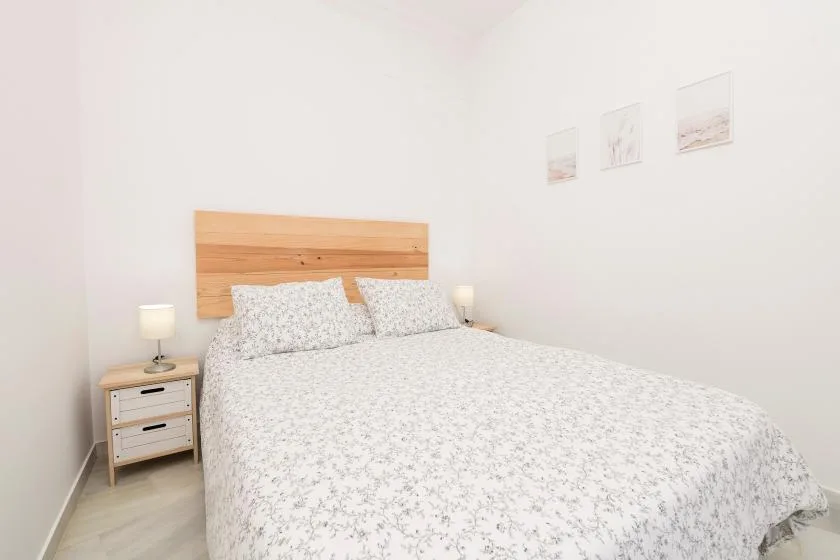 A bright bedroom with a large bed and light patterned bedding.