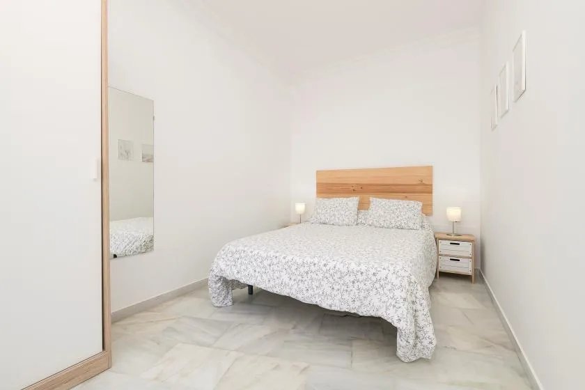 A bright bedroom with a double bed and matching bedside lamps.