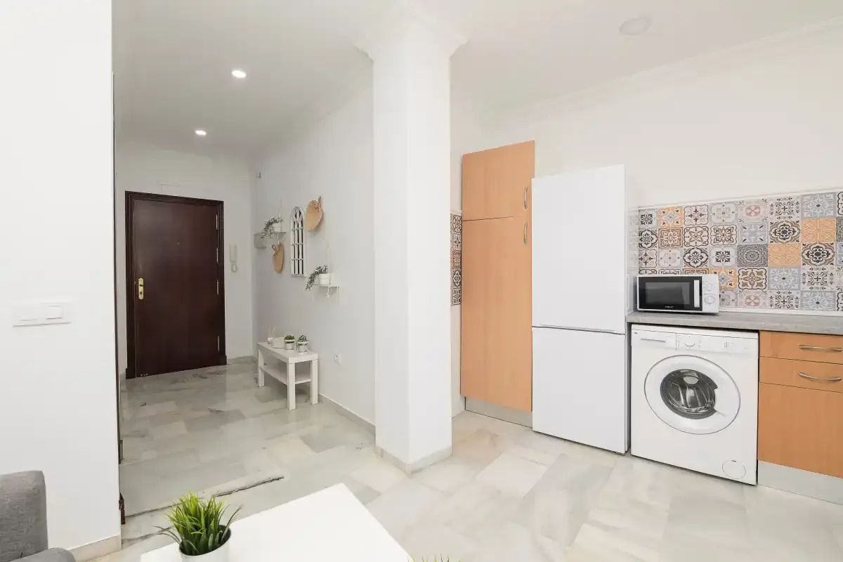 A bright kitchen area with a refrigerator, washing machine, and patterned backsplash.