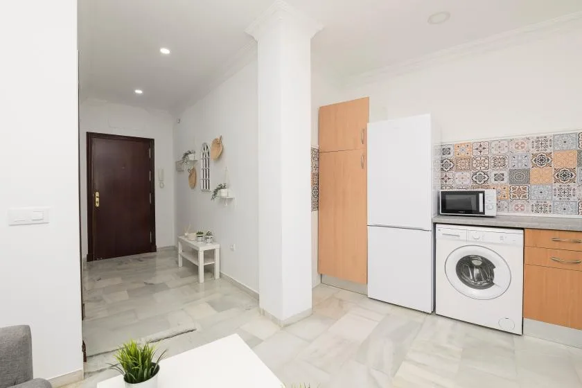 A bright kitchen area opens onto a tiled hallway with a dark entry door.