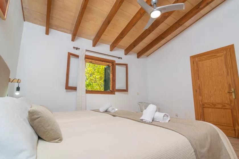 Un dormitorio con una cama grande bajo un techo inclinado con vigas de madera.