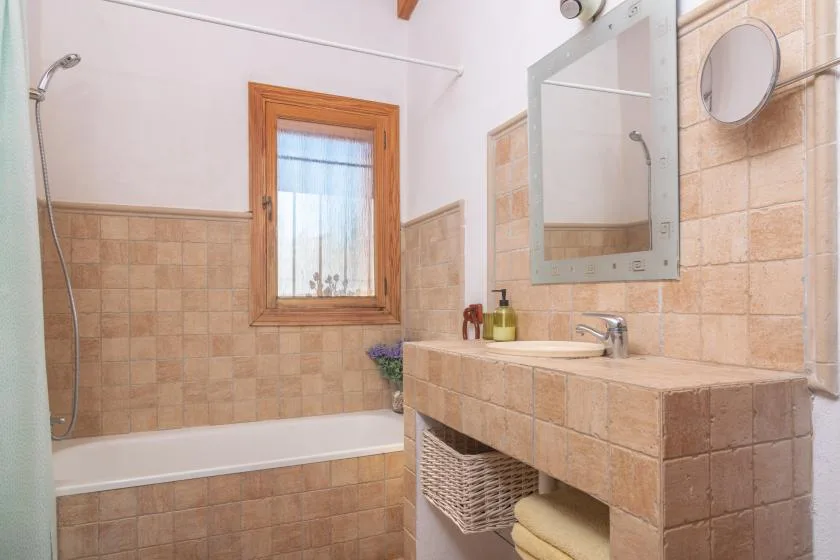 Un baño con azulejos, bañera, ventana y espejo de pared.