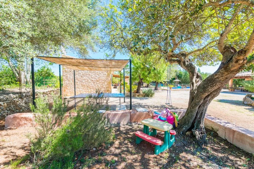 Una zona de picnic al aire libre tiene una mesa colorida bajo un árbol grande.