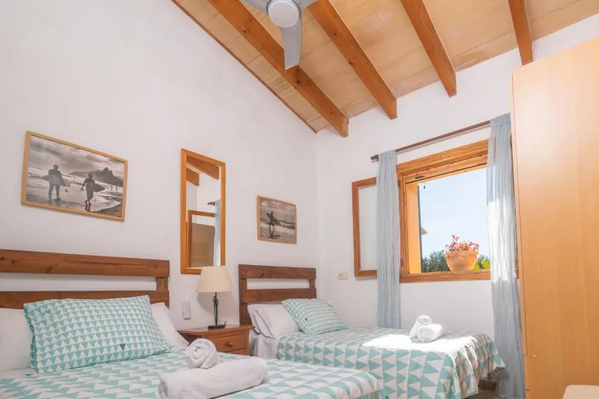 Un dormitorio con dos camas, ropa de cama estampada y una ventana con flores.