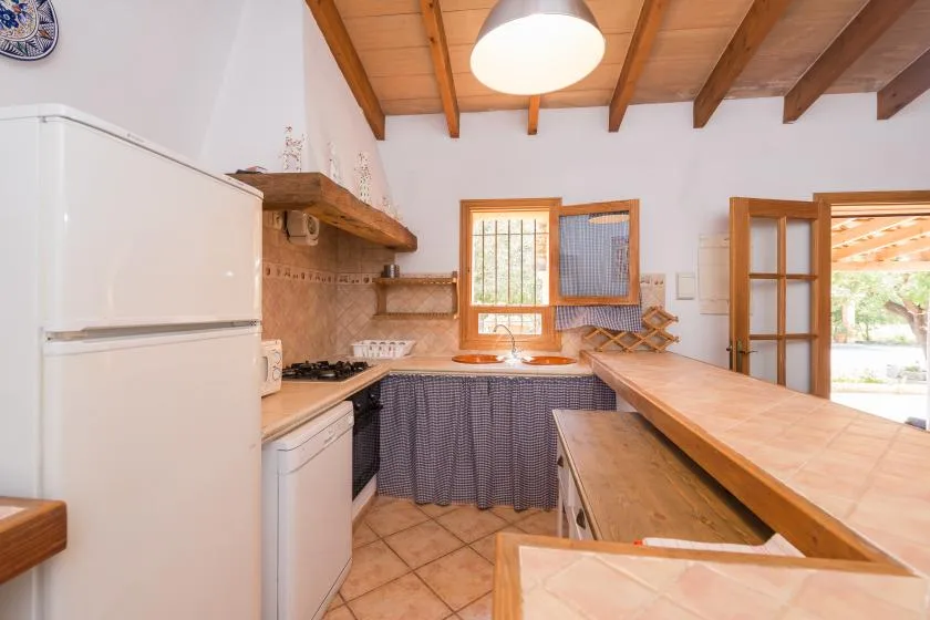 Una cocina con refrigerador, encimera y vigas de madera en el techo.