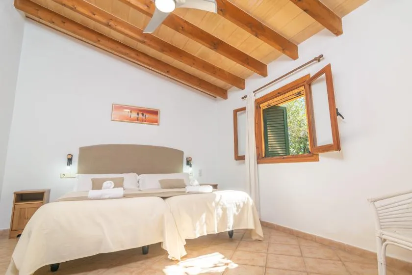 Un dormitorio luminoso con una cama doble bajo vigas de madera vistas.