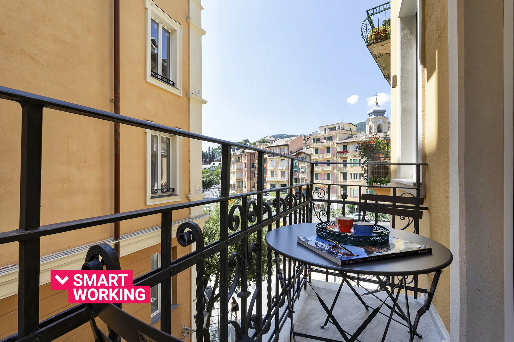 A small balcony with a round table and views of neighboring buildings.