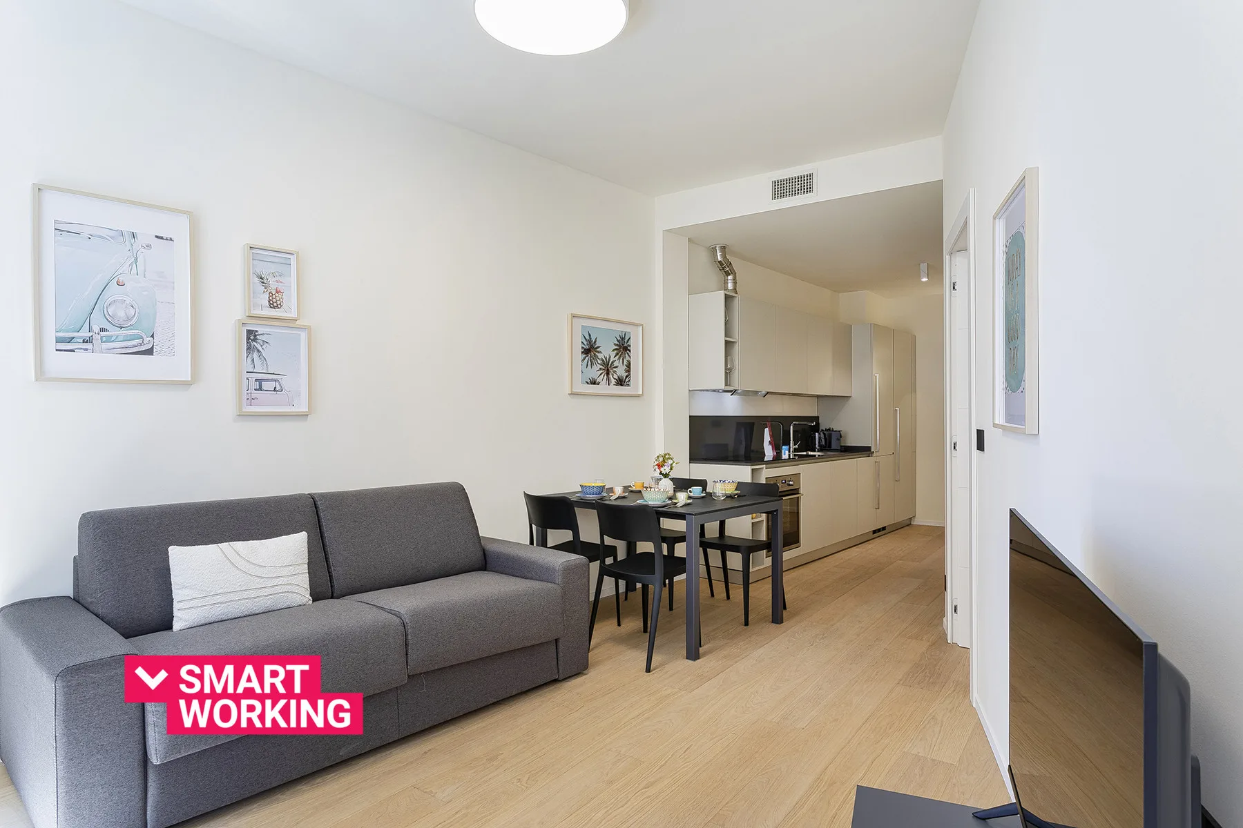 A bright living and dining area with a gray sofa and a table.