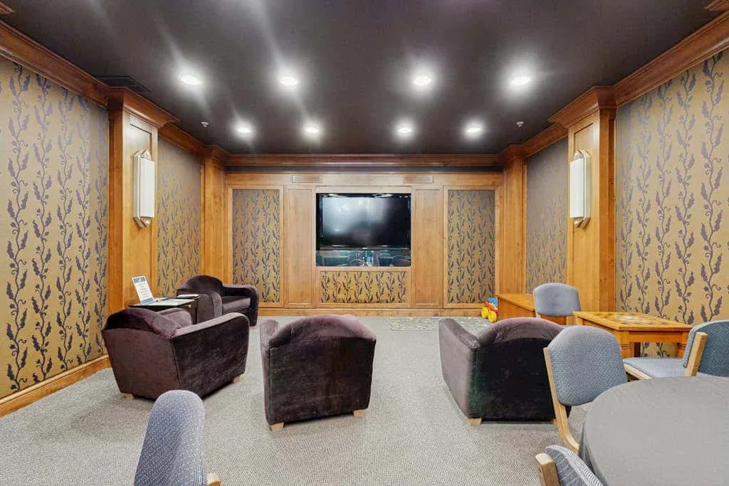 Una sala multimedia con televisor, asientos y una mesa.