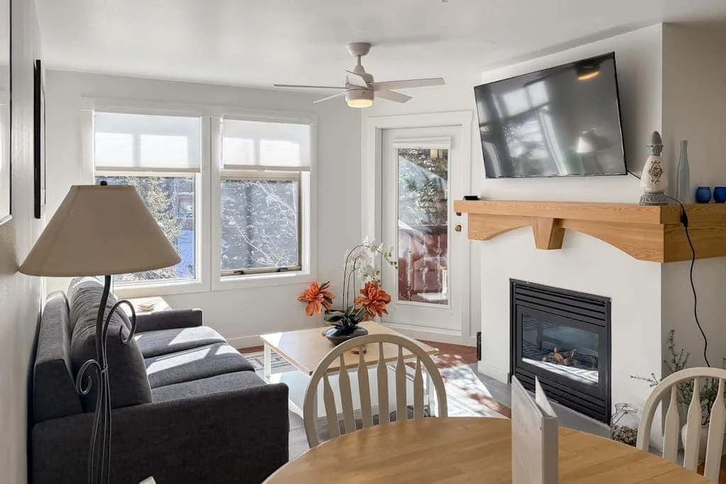 Una sala luminosa con asientos, una chimenea y ventanas grandes.