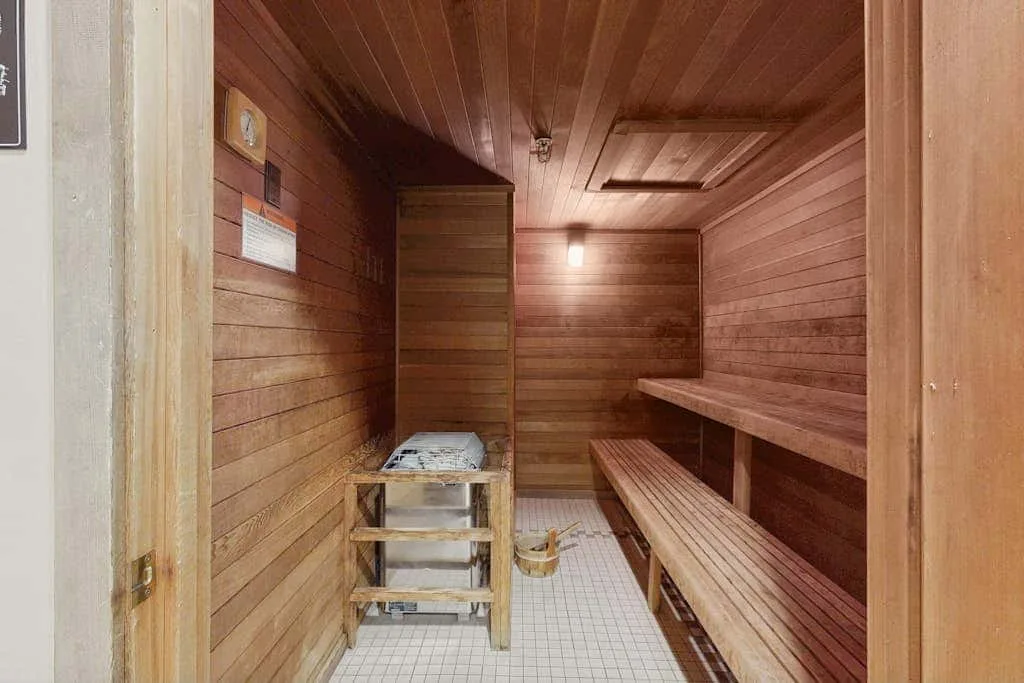 A wood-paneled sauna room with bench seating and a tiled floor.