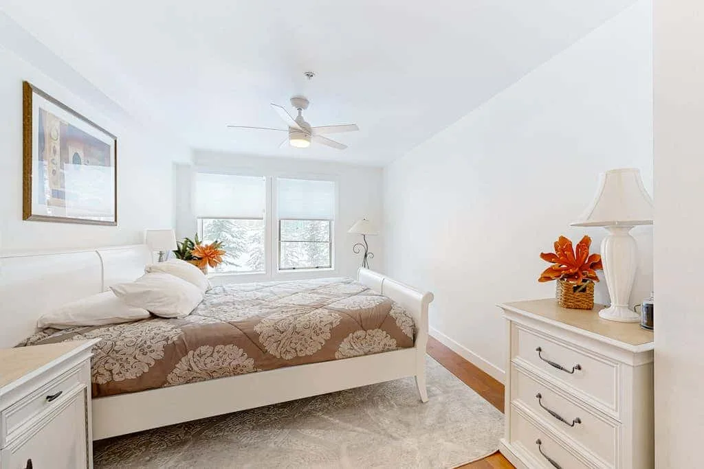 Un dormitorio luminoso con una cama, cómodas de noche y ventanas.