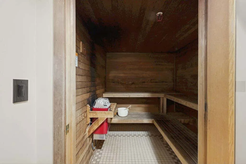 Una sauna revestida de madera, con asientos escalonados y suelo de baldosas.