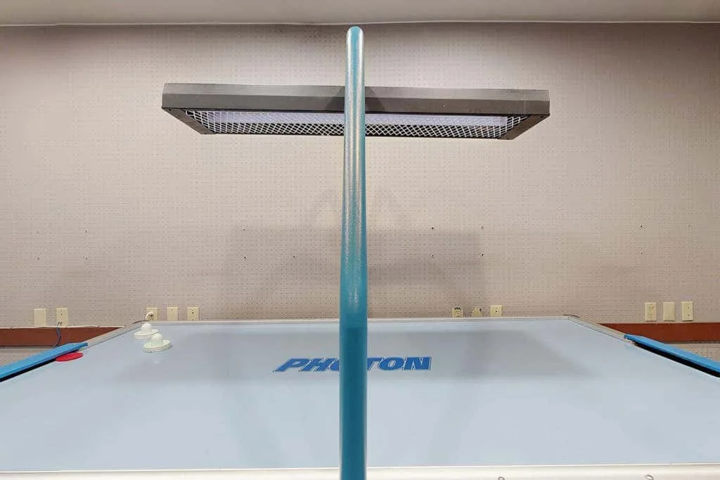 Una mesa de hockey de aire está bajo un estante montado en la pared.