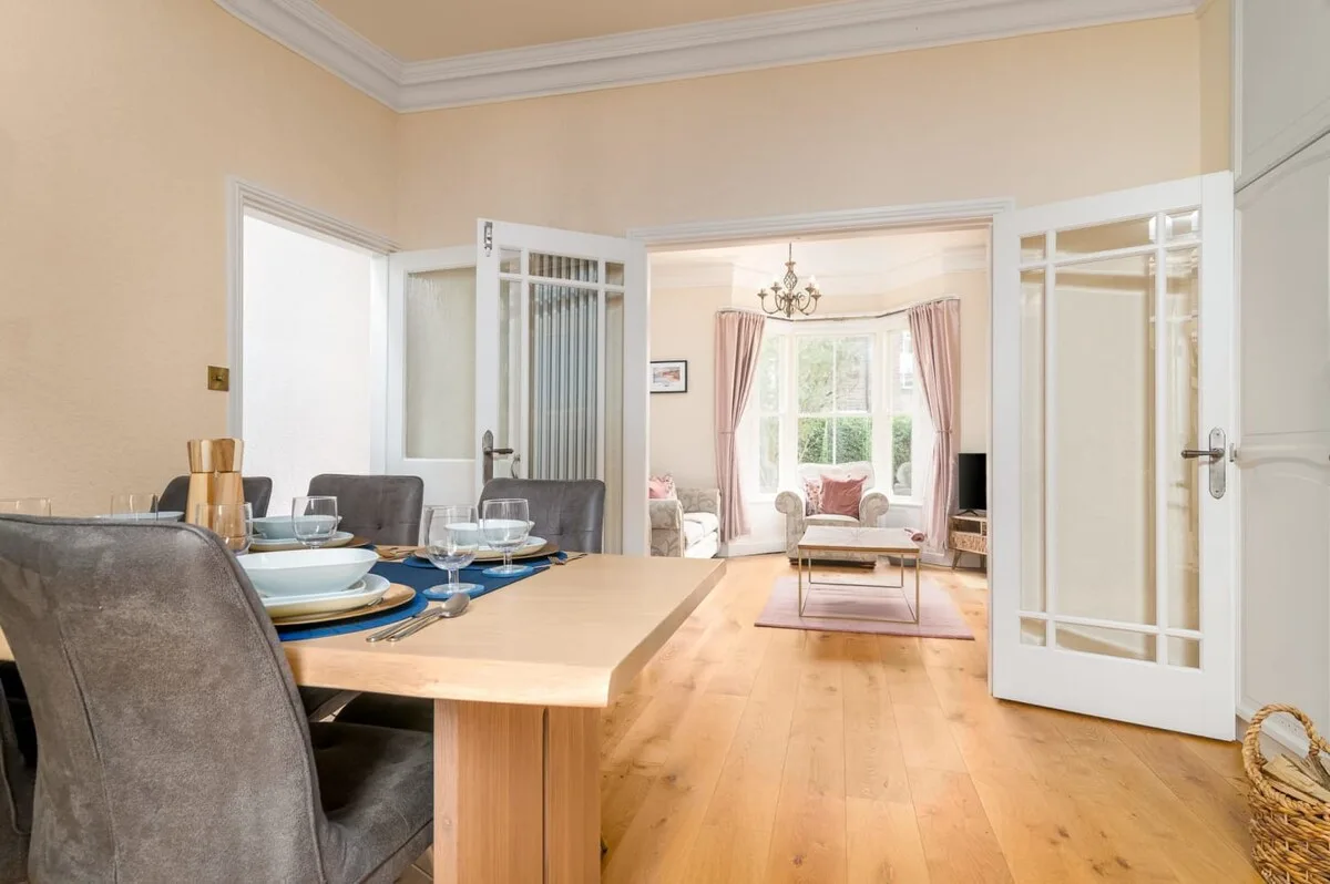A dining area opens through glass-paneled doors into a bright sitting room.