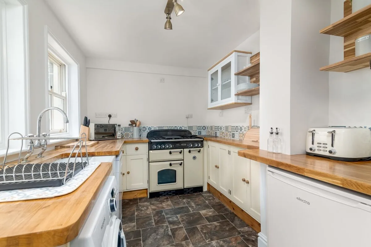 A bright kitchen with wooden countertops and a freestanding stove.