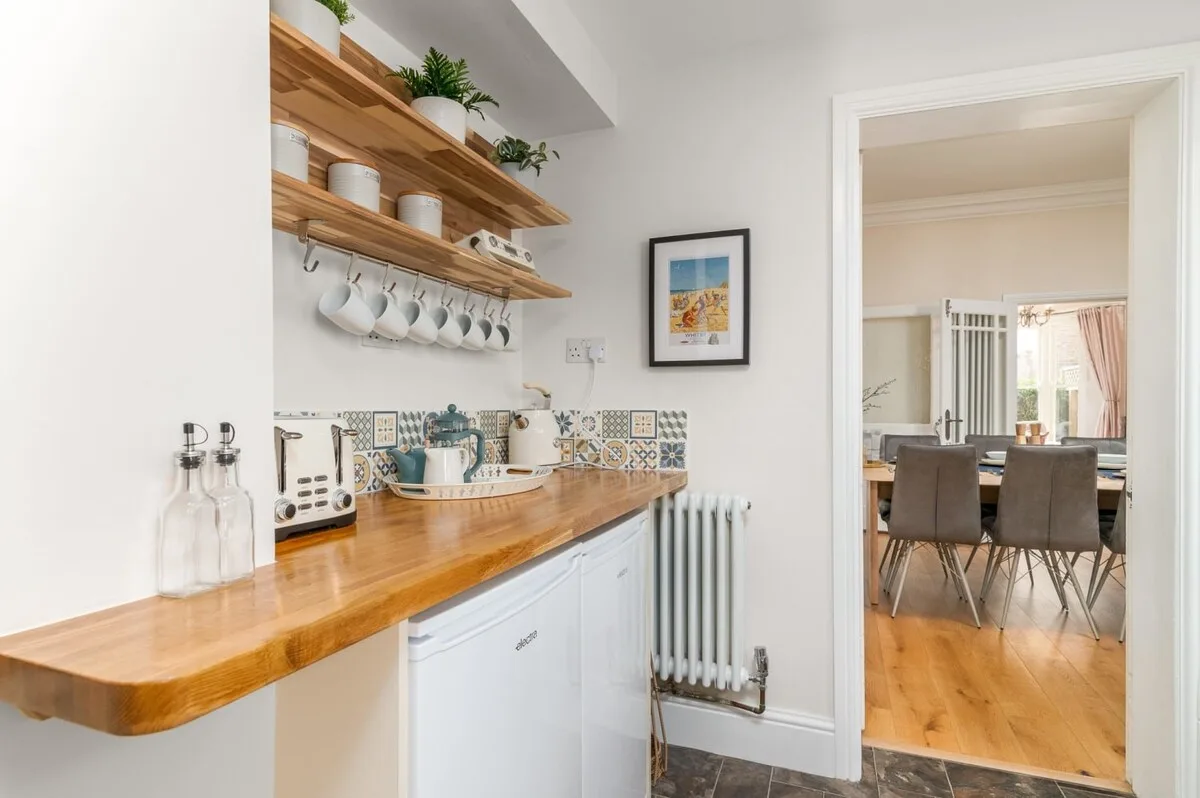 A bright kitchen with a wooden counter and open shelves.
