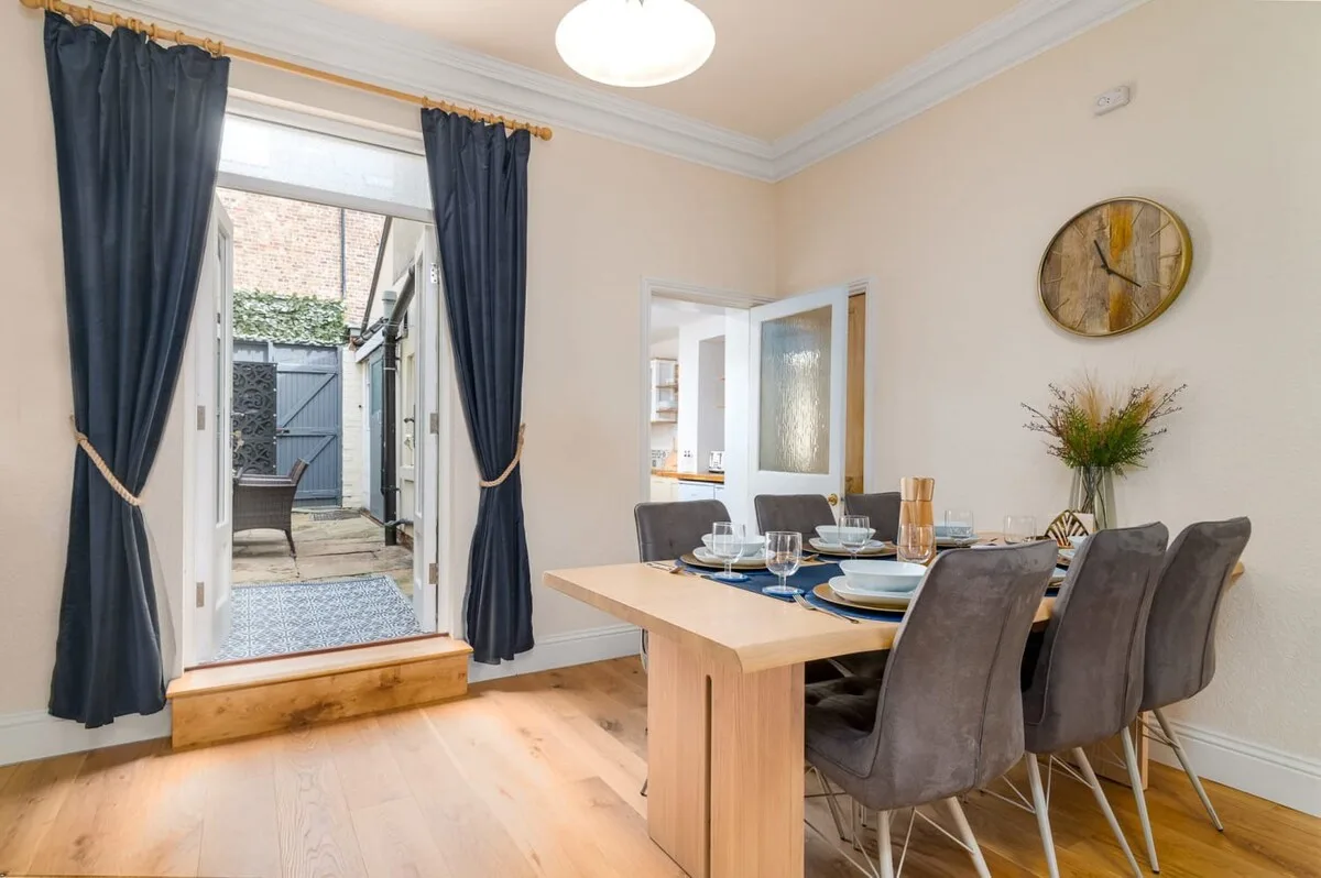 A dining area with a table set beside open doors leading to a patio.