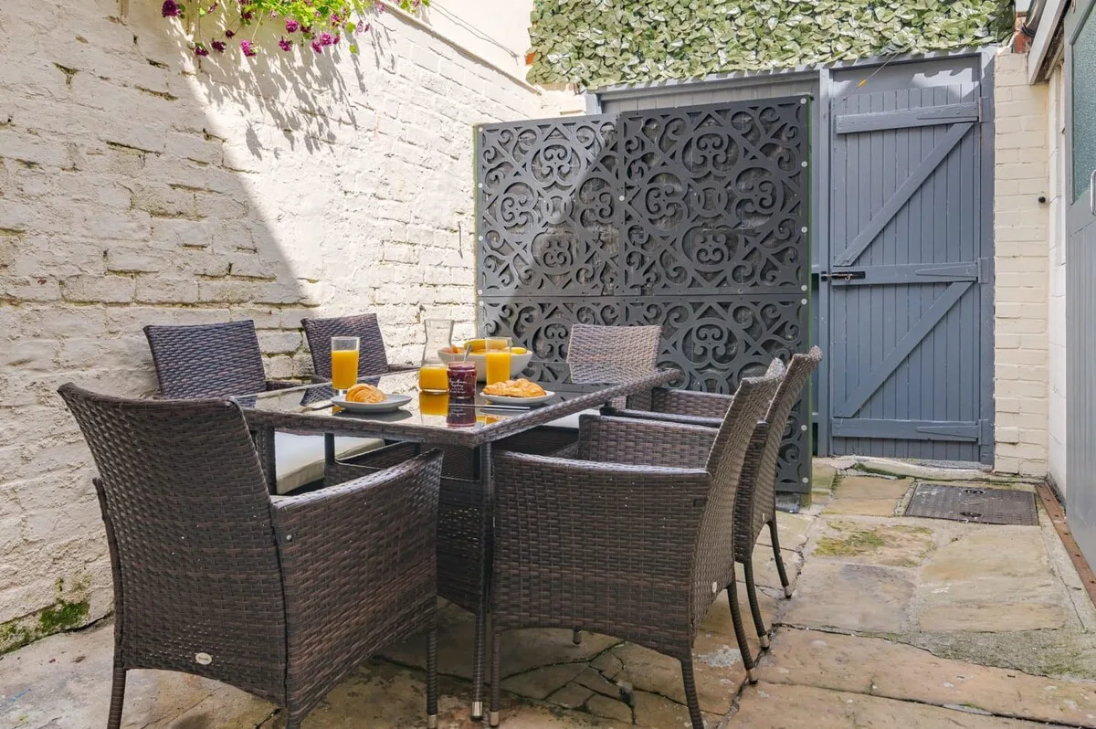 A paved courtyard dining area with outdoor seating and a decorative screen.